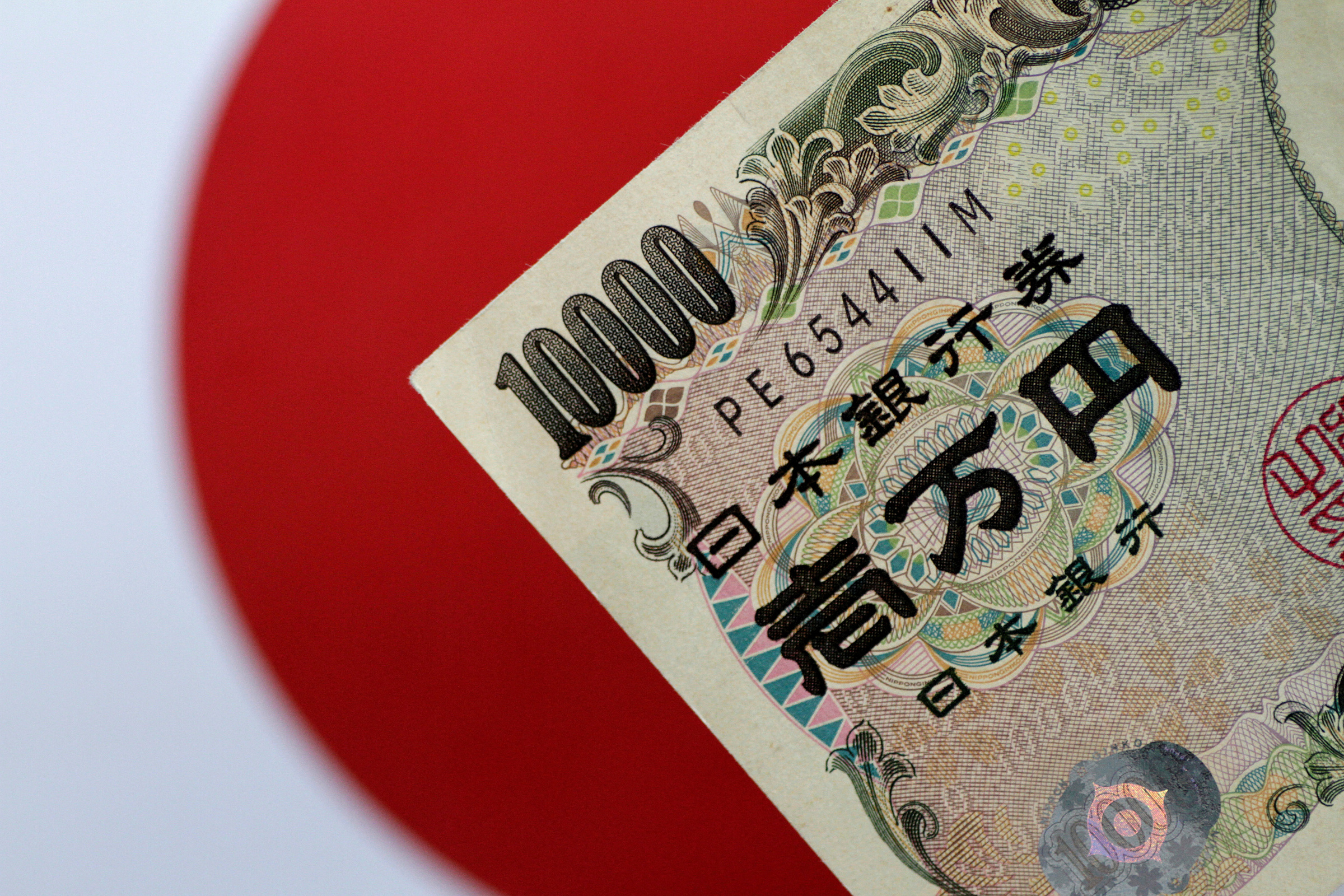 Một góc tờ tiền nội tệ chụp trên nền cờ Nhật Bản. Ảnh: Reuters